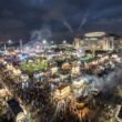 Aerial nighttime view of the Houston Rodeo carnival grounds at NRG Park, with colorful rides and a large crowd.